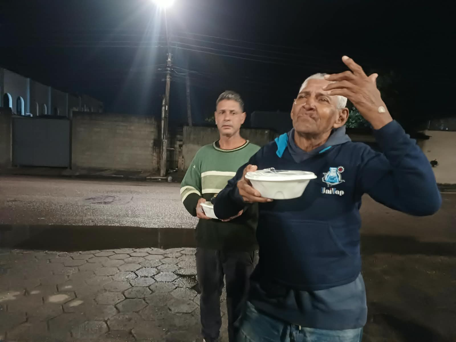 Senhor recebendo refeição quente durante ação social noturna